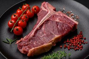 cru suculento carne t-bone bife com sal, especiarias e ervas foto