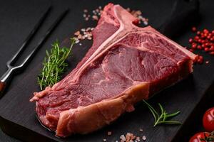 cru suculento carne t-bone bife com sal, especiarias e ervas foto