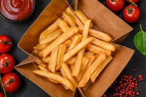 delicioso crocantes francês fritas com sal e especiarias dentro uma cartão caixa foto