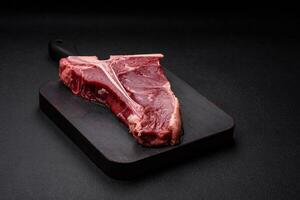 cru suculento carne t-bone bife com sal, especiarias e ervas foto