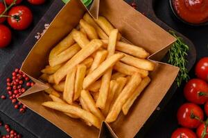 delicioso crocantes francês fritas com sal e especiarias dentro uma cartão caixa foto