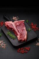 cru suculento carne t-bone bife com sal, especiarias e ervas foto