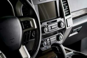 luxo carro direção roda e painel de controle com multimídia tela, confortável interior para a motorista foto