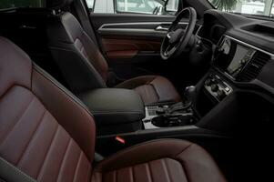 lado Visão do a interior do uma luxuoso carro com vermelho couro assentos, automático transmissão, direção roda e toque tela foto