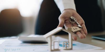 modelo de casa e chave na mesa para finanças e serviços bancários. conceito de hipoteca de compra de casa. foto