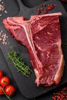 cru suculento carne t-bone bife com sal, especiarias e ervas foto