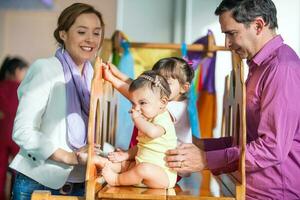 lindo dez meses bebê menina jogando com dela família. cedo estimulação para crianças conceito. foto