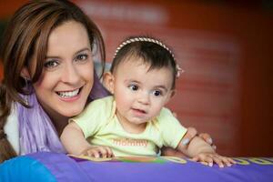 jovem mãe jogando com dela bebê filha. cedo estimulação para crianças conceito. foto