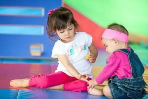 lindo pequeno menina jogando com dela dez meses bebê menina irmã. cedo estimulação para crianças e crianças conceito. foto