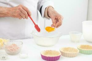 Senior mulher preparando a o preenchimento para uma delicioso queijo e presunto tartelete foto