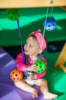 lindo dez meses bebê menina jogando com colorida bolas. cedo estimulação para crianças conceito. foto