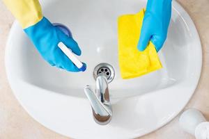 mãos com luvas de proteção limpando um banheiro. conceito de desinfecção ou higiene