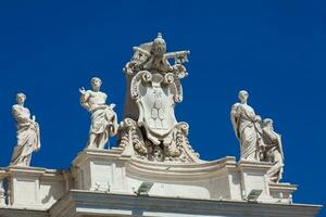 detalhe do a chigi casacos do braços e a estátuas do santos este coroa a colunatas do st. Peter quadrado construído em 1667 em a Vaticano cidade foto