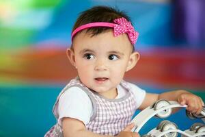 lindo dez meses bebê menina jogando com uma pandeiro. cedo estimulação para crianças conceito. foto