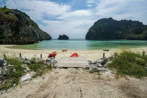 de praia em a ilha dentro myanmar Onde lá estão não pessoas lá estão 4 catak barcos em a de praia. a água é claro, esmeralda verde, uma baía com uma pequeno ilha dentro frente do a baía. foto