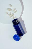 aberto dietético suplemento garrafa com transparente cápsulas em branco pódio. saudável vida, vitaminas e minerais foto