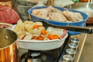 chefe de cozinha derrama frango caldo a partir de cobre Panela para dentro prato do frango pernas foto