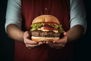 a cozinhar detém uma Hamburger dentro dele mãos. foto