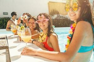 grupo do amigos dentro roupa de banho beber uma coquetel dentro uma natação piscina foto