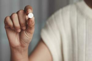 ásia mulher mão segurando uma branco comprimido para médico e cuidados de saúde conceito. foto