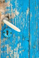 detalhe da velha porta de madeira azul-petróleo e maçaneta de metal