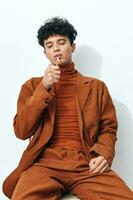 sentado homem na moda fumar aluna cigarro lindo pensativo retrato bege moda face estúdio estilo de vida foto
