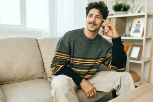homem freelance falando o negócio sorrir casa estilo de vida sofá célula sentado telefone conexão casa masculino foto