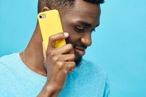 Móvel homem telefone tecnologia amarelo sorrir jovem africano digitando Preto fundo feliz foto