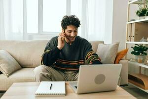 homem sofá alegre cara trabalhando conectados computador portátil estilo de vida freelance computador bonito casa sorrir o negócio foto