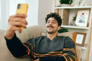 homem digitando quarto vivo selfie casa sentado estilo de vida sofá mensagem telefone comunicação tecnologia foto