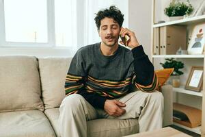 freelance homem sorrir sofá célula casa telefone Smartphone falando sentado relaxante estilo de vida foto