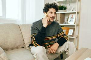 homem cara estilo de vida Smartphone sofá sorrir telefone sentado célula sofá casa freelance falando foto