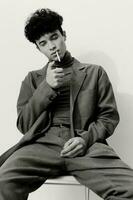 hipster homem pensativo e fumar cigarro aluna Preto sentado moda branco moderno retrato foto