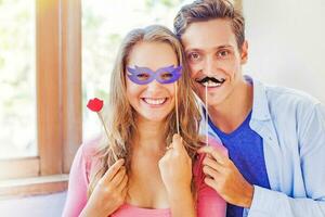 casal posando com bastão bigode e hipster Óculos acessórios. homem e mulher dentro festa fantasias foto