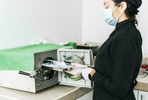 dentista com uma dental esterilizador, uma dentista esterilizando dele ferramentas, uma dentista com uma dental autoclave, fechar acima do uma dentista com uma vapor esterilizador foto