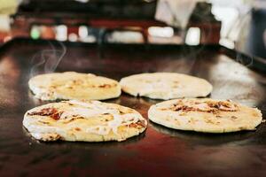 tradicional salvadorenho pupusas com derretido queijo em uma grade, tradicional queijo pupusas em a grade. lado Visão do quatro tradicional crocantes pupusas em a grade foto