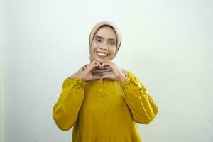 retrato do sorridente ásia muçulmano mulher mostrando coração gesto isolado sobre branco fundo foto