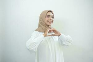 retrato do sorridente ásia muçulmano mulher mostrando coração gesto isolado sobre branco fundo foto