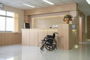 vazio moderno balcão de recepção de madeira com monitor e cadeira de rodas no hospital foto