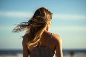 traseiro Visão do uma lindo jovem mulher com cabelo dentro a vento em a de praia. ai generativo foto