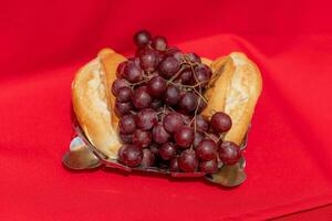 elementos do a último ceia do Jesus pão, uvas e vinho em uma vermelho pano com severo iluminação foto