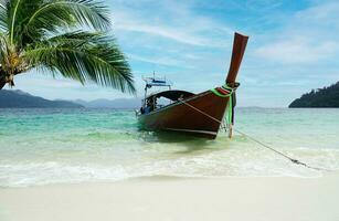 uma barco este conduz turistas para uma branco de praia perto a coco árvore foto