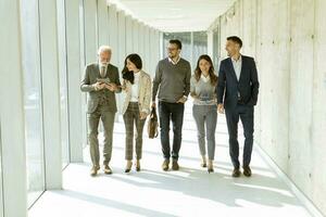 grupo de profissionais de negócios corporativos caminhando pelo corredor do escritório foto