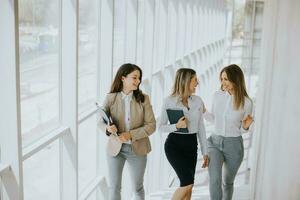 três jovem o negócio mulheres caminhando em escadas dentro a escritório corredor foto