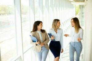 três jovem o negócio mulheres caminhando em escadas dentro a escritório corredor foto