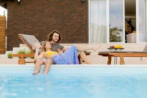 jovem casal relaxante de a natação piscina dentro a casa quintal foto