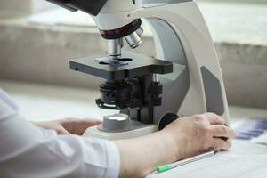 parte do uma laboratório microscópio dentro uma hospital com a mãos do uma laboratório assistente. foto