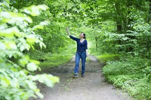 feliz meia idade mulher anda em através a verão floresta. foto