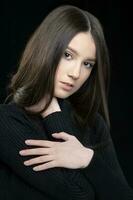 vertical retrato do uma lindo dezessete ano velho menina com grandes cabelo contra uma Sombrio fundo. foto