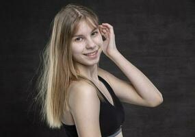 uma Adolescência menina com espinhas em dela face dentro uma Esportes camisa em uma Sombrio fundo. foto